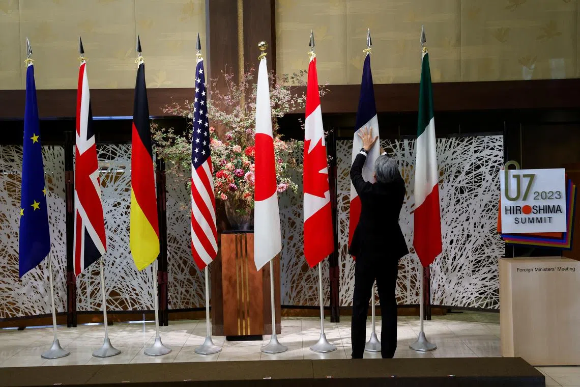 An official adjusts the flags before G7 foreign ministers gather for a family photo during their meetings in Tokyo, Japan, November 8, 2023. REUTERS/Jonathan Ernst/Pool/File Photo