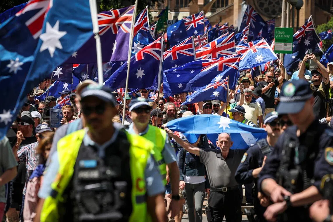 Protesters, watched by police, participate in the March for Australia rally in central Sydney on Oct 19, 2025. PHOTO: AFP