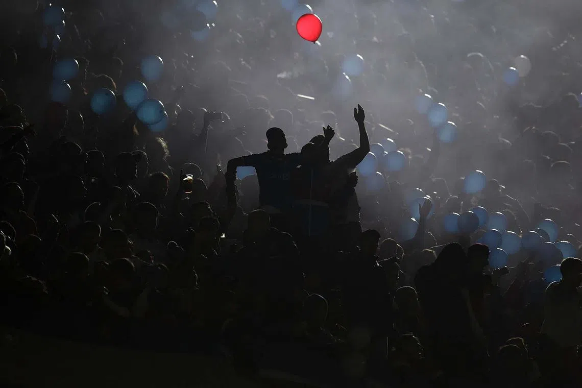 TOPSHOT - Fans of Nacional cheer for their team in the dark as they hold balloons before the Copa Libertadores round of 16 first leg football match between Uruguay's Nacional and Brazil's Sao Paulo at the Gran Parque Central stadium in Montevideo on August 15, 2024. (Photo by DANTE FERNANDEZ / AFP)