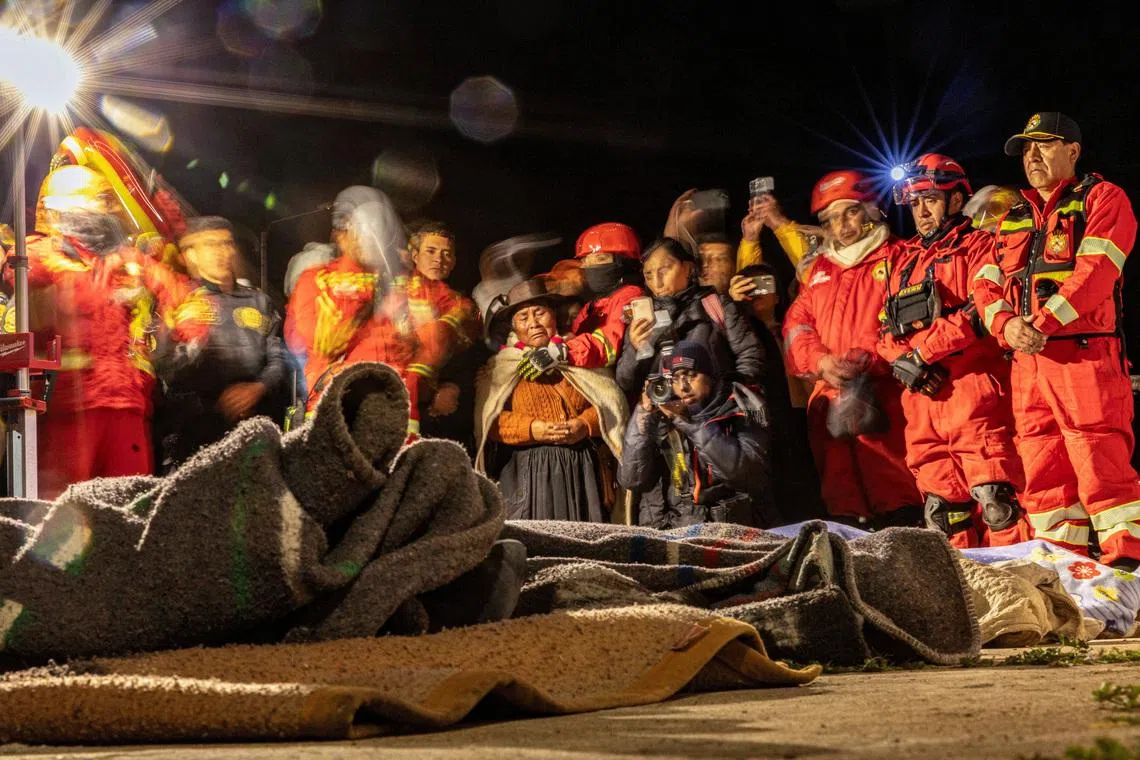 People in Chupuro, Peru, on July 19 praying next to the bodies of four victims of an earthquake that struck the centre of the country a day ago.