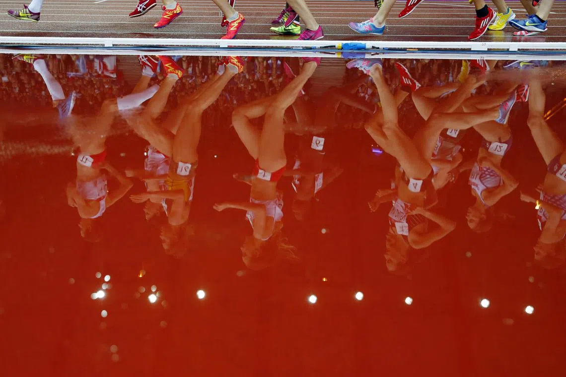 FILE PHOTO: Runners are reflected in a puddle as they compete in the women's 5000m race at the 2014 Commonwealth Games in Glasgow, Scotland, August 2, 2014.      REUTERS/Phil Noble