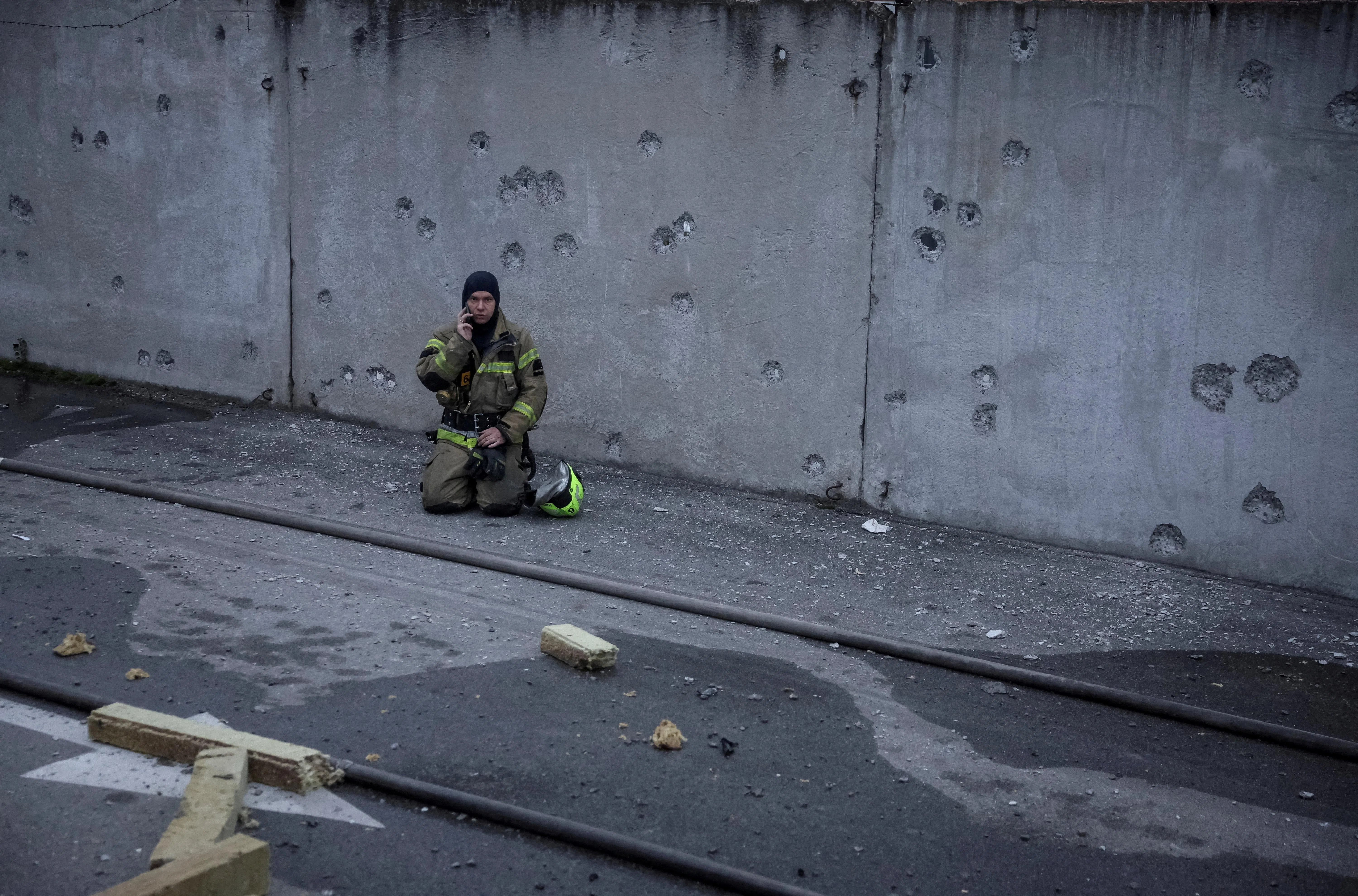 A rescuer taking a break near a wall with shrapnel holes at the site of a shopping centre hit by a Russian missile attack, in Kyiv, Ukraine, on Oct 22.