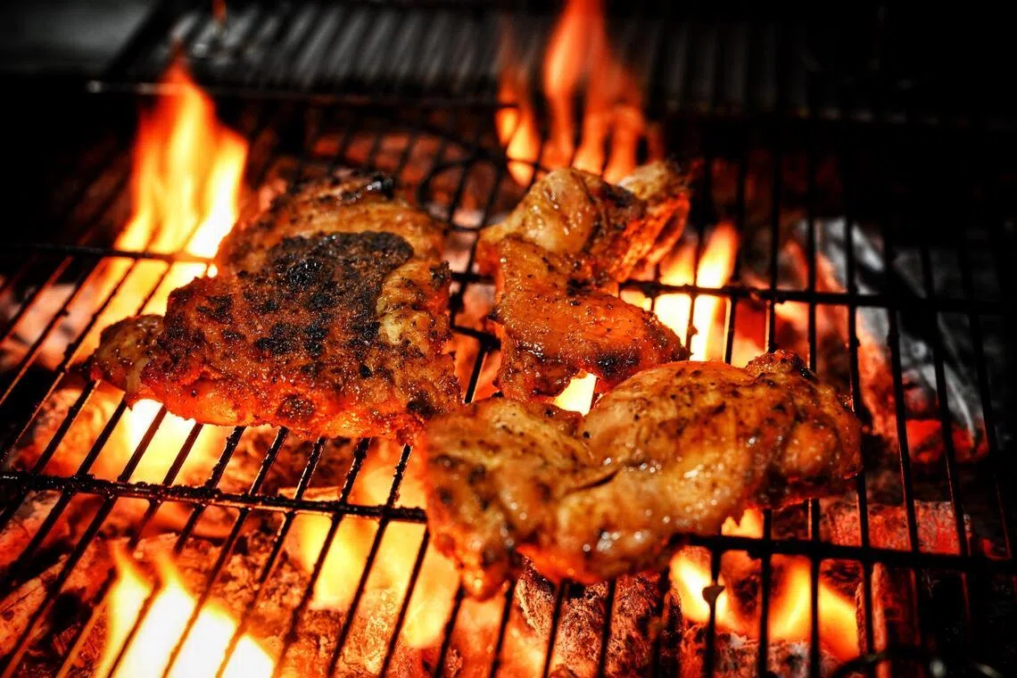 Mr Omar Alnaimi cooks meat with an open fire grill using charcoal.