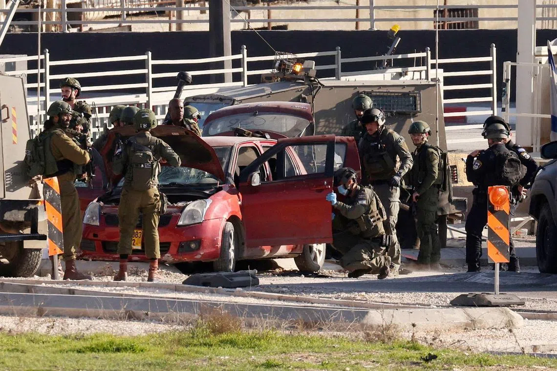 Israeli security forces surround a car which was reportedly used by a Palestinian to ram into Israeli soldiers at the entrance to Fawwar refugee camp, south of Hebron in the occupied West Bank.