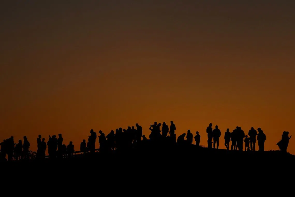 Displaced Palestinians try to get internet service on their phones through the Egyptian networks to communicate with their relatives, amid the ongoing conflict between Israel and Hamas, in Rafah in the southern Gaza Strip, March 4, 2024. REUTERS/Mohammed Salem/File Photo