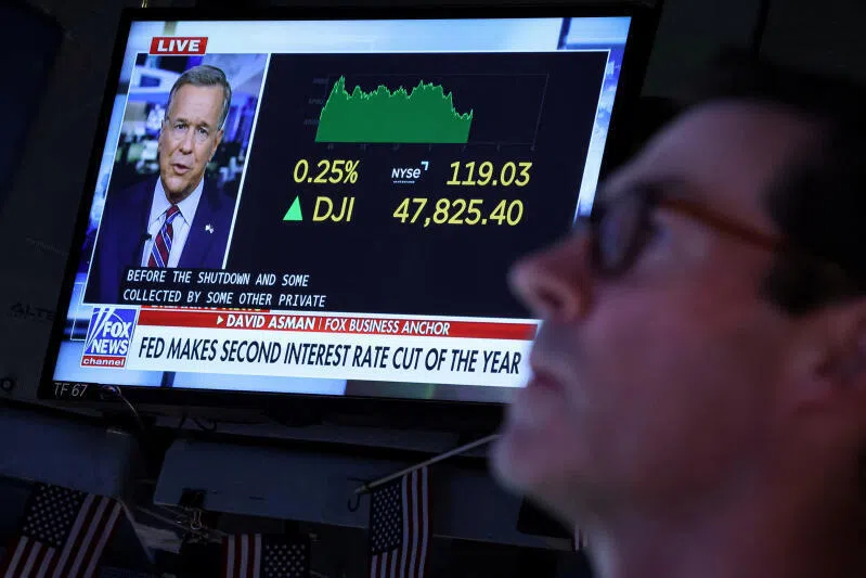 A screen displays a headline about the US Federal Reserve rate cut announcement as a trader works on the floor of the New York Stock Exchange in New York City.