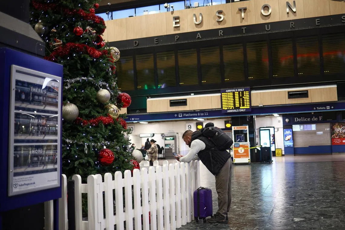 A person in front of a blank departure screen at Euston station, as rail workers go on strike in London, on Jan 5, 2023.