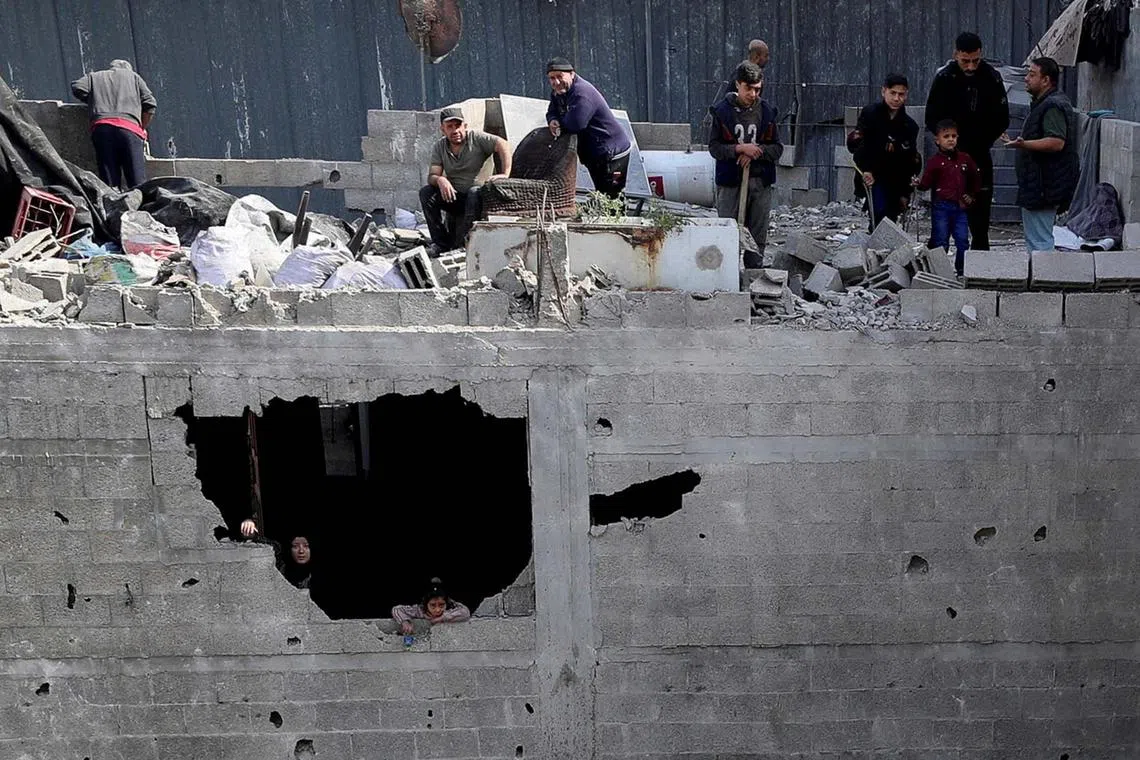 Palestinians looking on at the site of an Israeli strike on a house, in Jabalia, in the northern Gaza Strip April 16, 2025. 