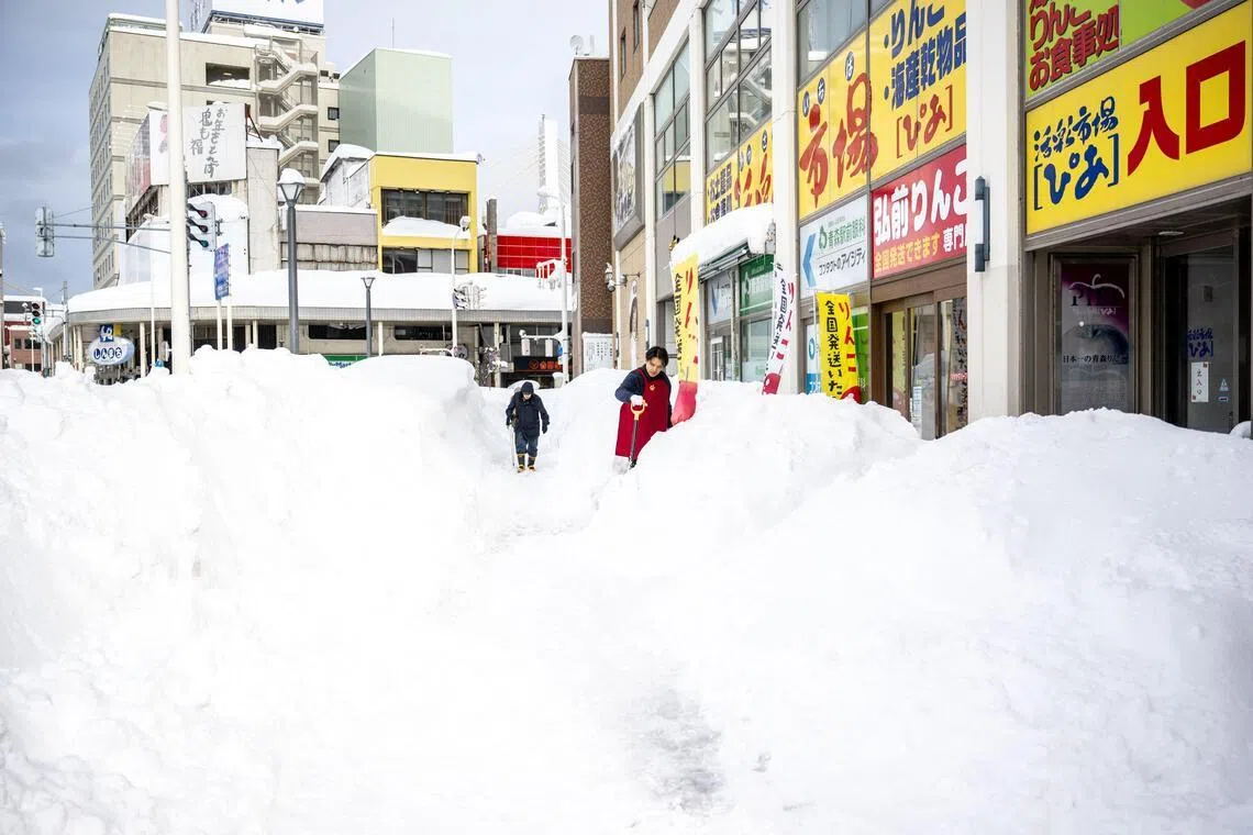 A shop employee shovels the snow in front of a shop in Aomori prefecture on Jan 30, 2026. 