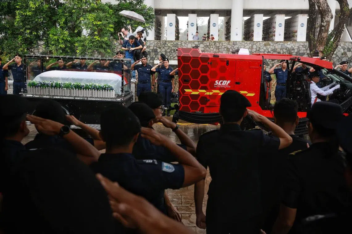 A contingent of SCDF officers saluting the Light Fire Attack Vehicle carrying Sgt (1) Edward H. Go's body at Mandai Crematorium on Tuesday afternoon.