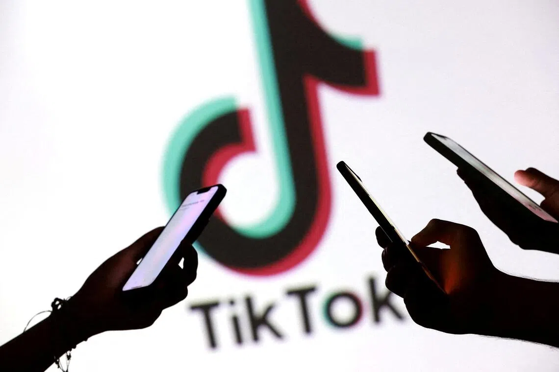 FILE PHOTO: Teenagers pose for a photo while holding smartphones in front of a TikTok logo in this illustration taken September 11, 2025. REUTERS/Dado Ruvic/Illustration/File Photo