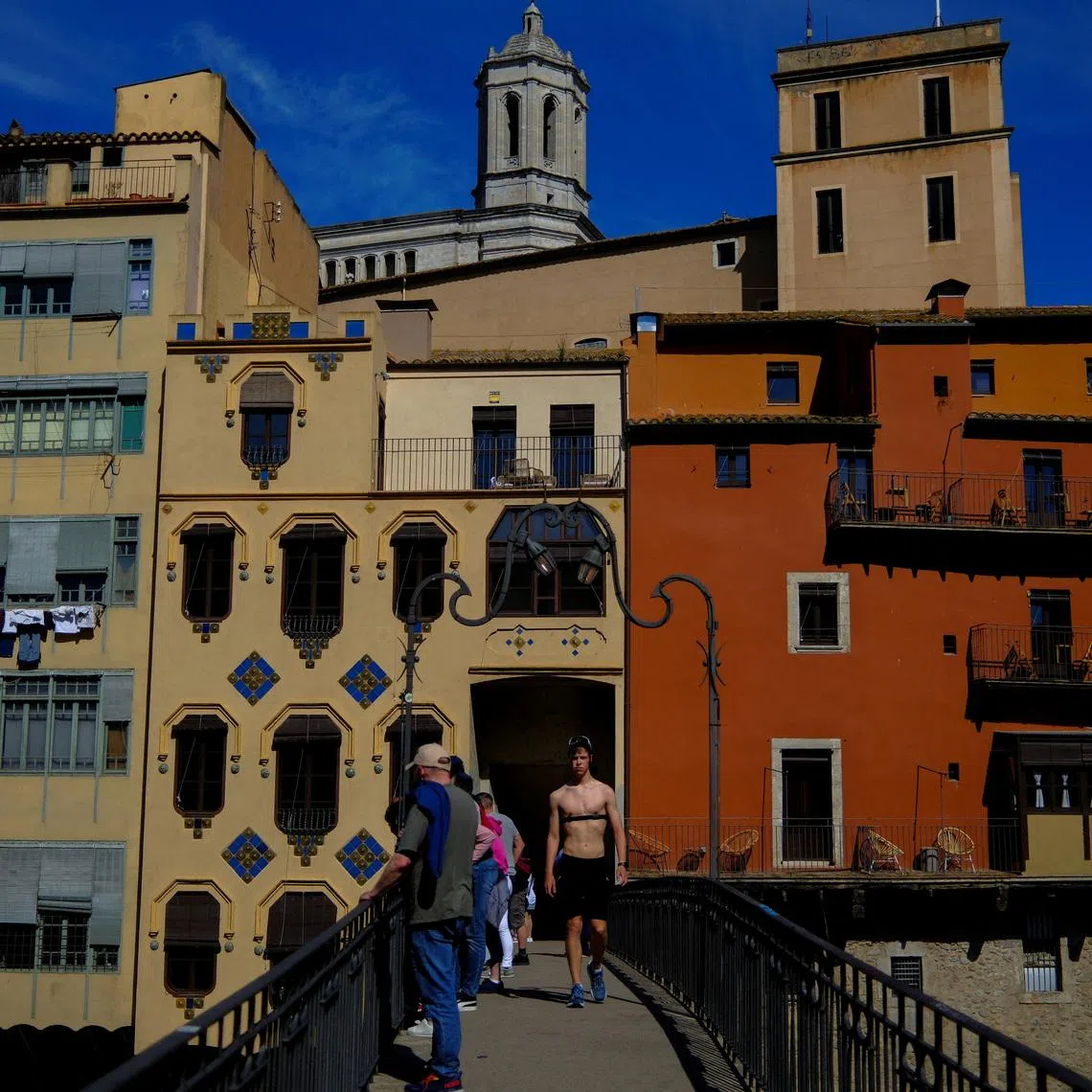 Tourists stand on a bridge in Girona, Spain, April 6, 2026. REUTERS/Nacho Doce