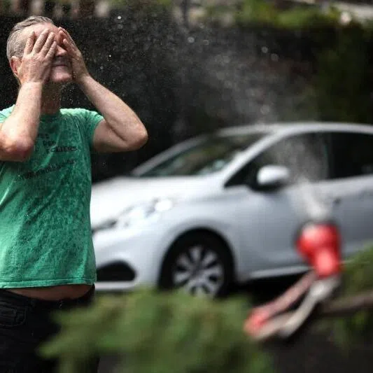 A man cools off in front of a hose spraying water in Paris on June 18, 2026.