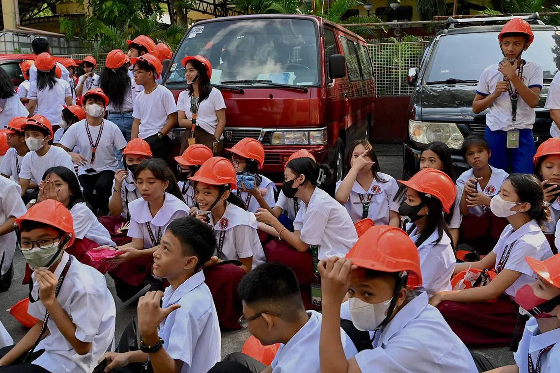 Students gather outdoors after evacuating from their school building in Manila on Oct 13 after a magnitude 5.2 earthquake struck about 100 kilometres south of the Philippine capital. 