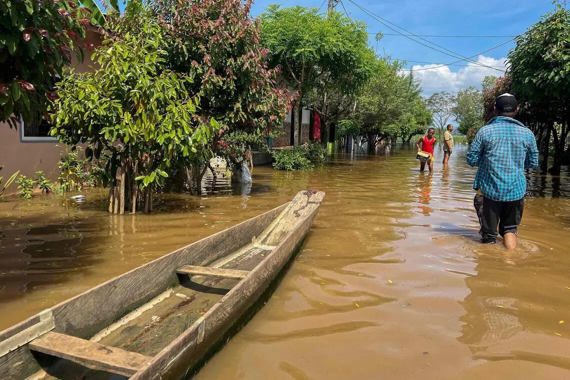 People walking on a flooded street in Lorica, in Colombia's Cordoba department, on Feb 9.
