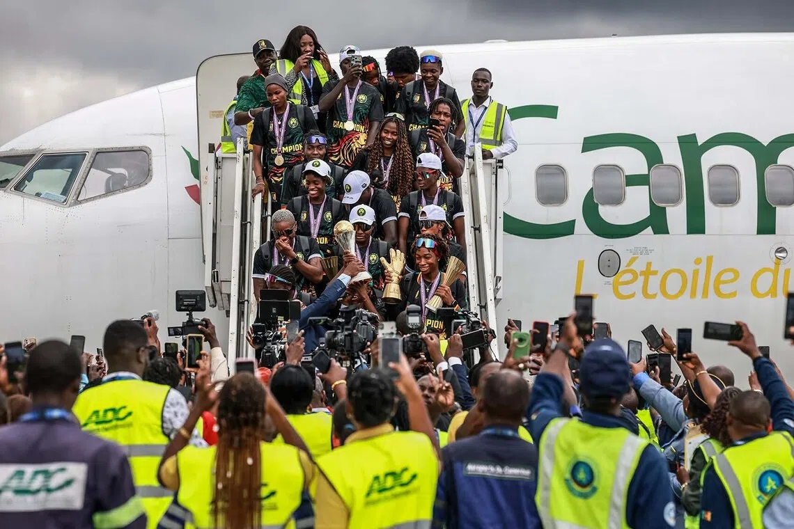 TOPSHOT - Cameroon’s national women's football team "The Indomitable Lionesses" players step off the plane after arriving at the Yaounde Nsimalen International Airport in Yaounde, August 17, 2026. Cameroon were crowned champions of the Women's Africa Cup of Nations (WAFCON) after defeating Malawi 3-0 in the final on August 16 in Morocco. (Photo by Daniel BELOUMOU OLOMO / AFP)