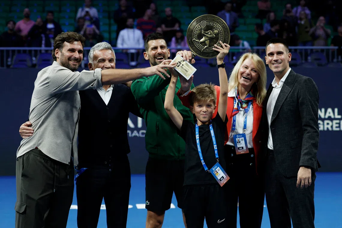 Tennis - ATP 250 - Hellenic Championship - Telekom Center Athens, Marousi, Greece - November 8, 2025 Serbia's Novak Djokovic celebrates with the trophy and his parents, Dijana Dokovic and Srdjan Djokovic, brothers Marko Djokovic and Djordje Djokovic, and his son Stefan after winning his final match against Italy's Lorenzo Musetti REUTERS/Louiza Vradi