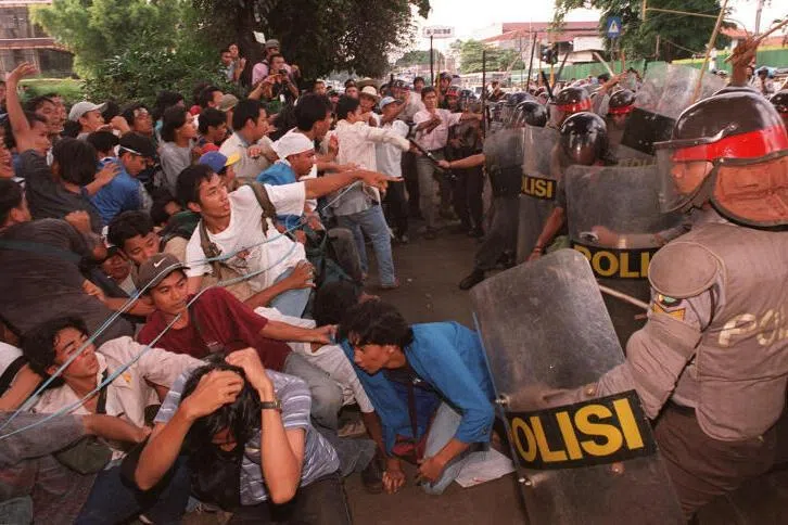 Indonesian students fall as riot policemen charge-in during an anti-government protest that turned violent at the gate of the Sahid University in Jakarta, on April 29, 1998.
