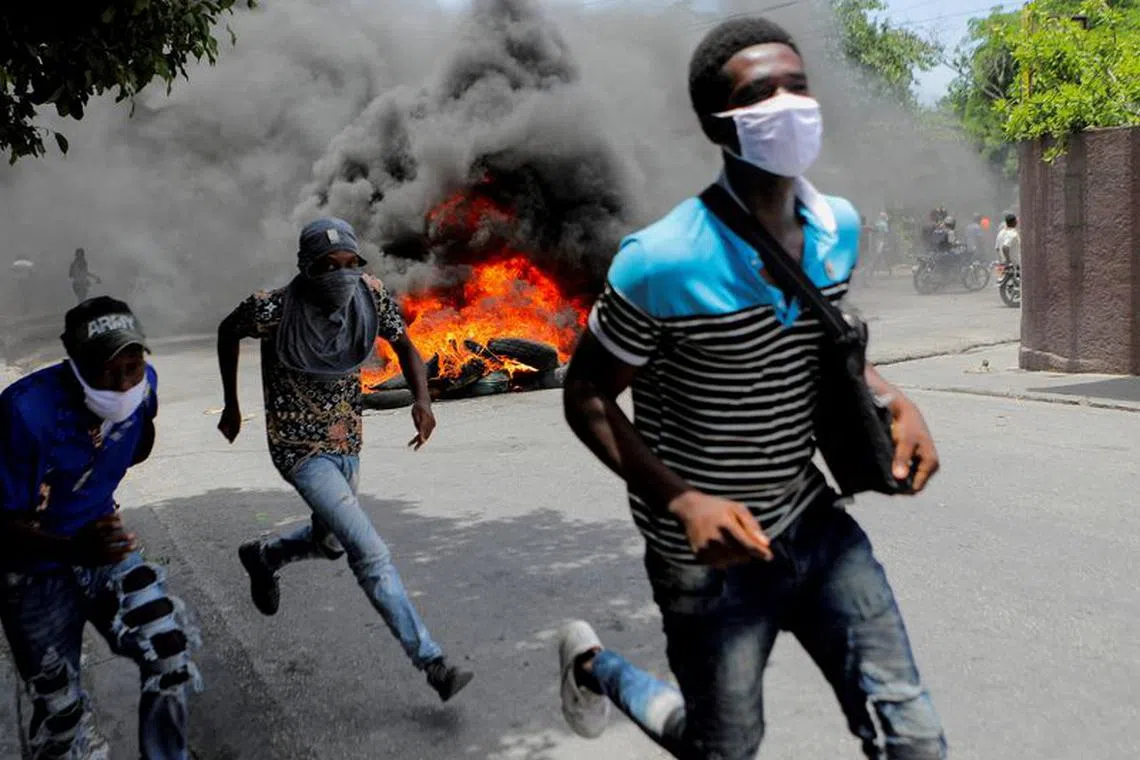 FILE PHOTO: Men run next to burning tires during a protest demanding an end to gang violence, in Port-au-Prince, Haiti, August 14, 2023. REUTERS/Ralph Tedy Erol/File Photo