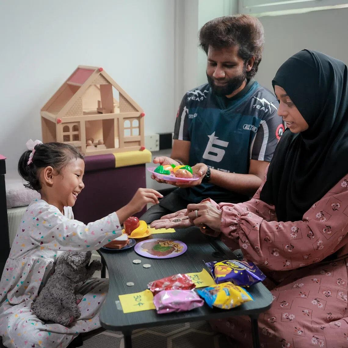 Madam Nasrin Shah Beevi and her husband, Mr Nizamudheen Ishak role-playing as a cashier, selling food items to their six-year-old daughter, Nur Zahirah Nizamudheen.