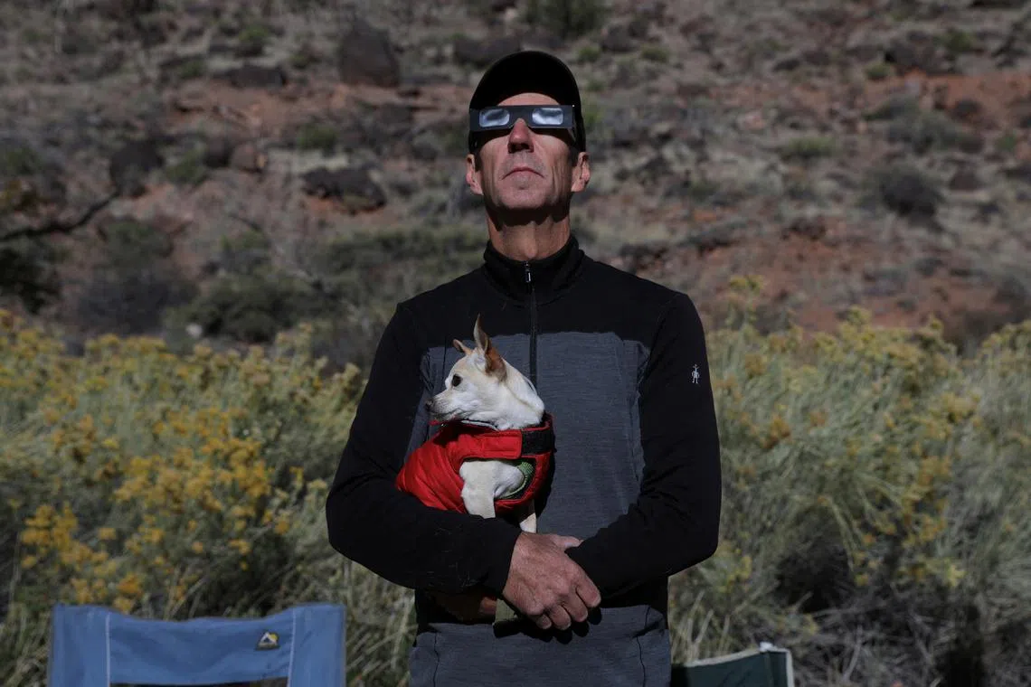 Jim Thompson, 65, a retiree of Salt Lake City, holding his dog named Rowdy, while watching the solar eclipse from Capitol Reef National Park in Torrey, Utah, US, on Oct 14, 2023. 