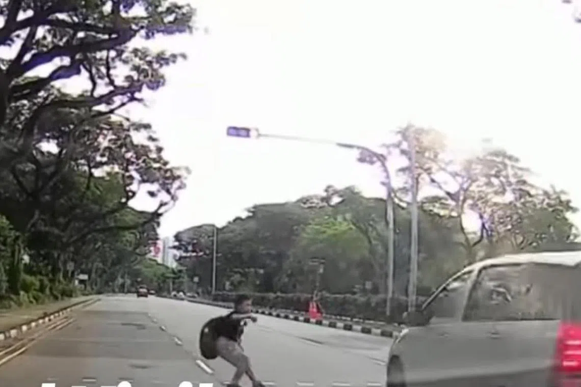 The student can be seen running across the road after the traffic light for pedestrians turns green. 