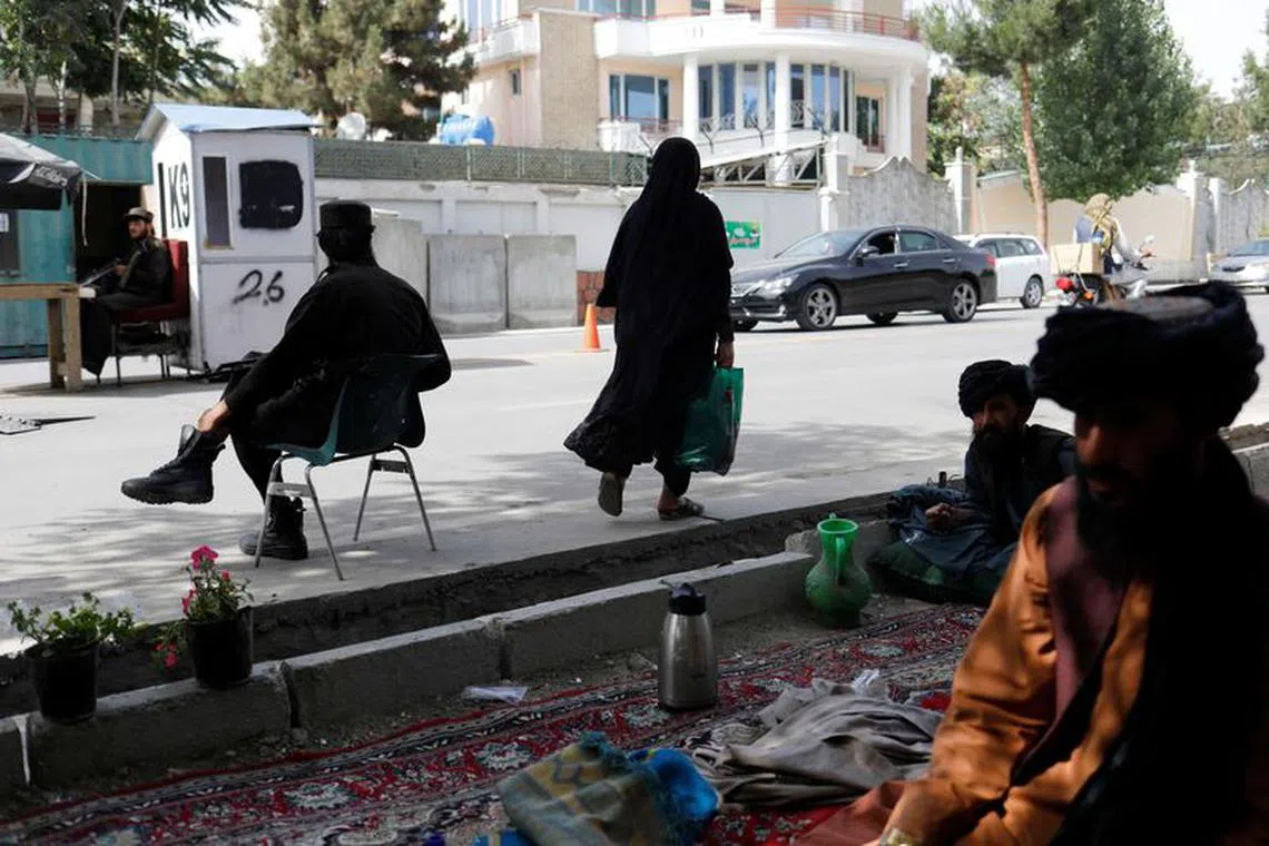 An Afghan woman walks among Taliban soldiers at a checkpoint in Kabul, Afghanistan, July 6, 2023. REUTERS/Ali Khara/File Photo