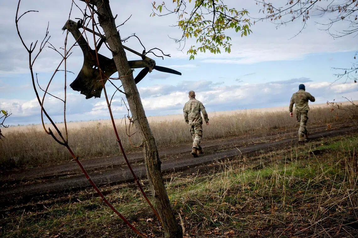 Ukrainian soldiers passing the remains of a Russian drone in the Zaporizhzhia region of Ukraine, in October 2025.