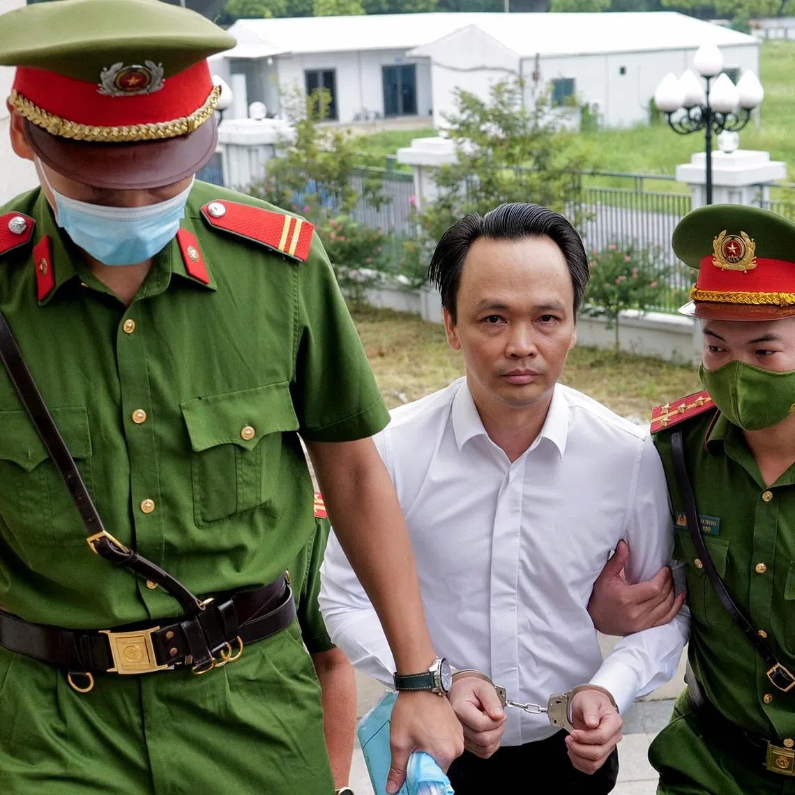 (FILES) Former Vietnamese property and aviation tycoon Trinh Van Quyet (C) is escorted by policemen to court for his trial on fraud charges in Hanoi on July 22, 2024. Trinh Van Quyet, who owned the FLC empire of luxury resorts, golf courses, and budget carrier Bamboo Airways, was jailed for 21 years on August 5 for fraud and stock market manipulation worth $146 million, state media said. (Photo by Anh TUC / AFP)