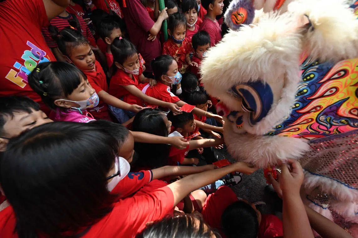 Children give money to lion dance performers at a school as part of festivities to welcome the upcoming Lunar New Year of the Rabbit in Solo, Central Java on Jan 19, 2023.