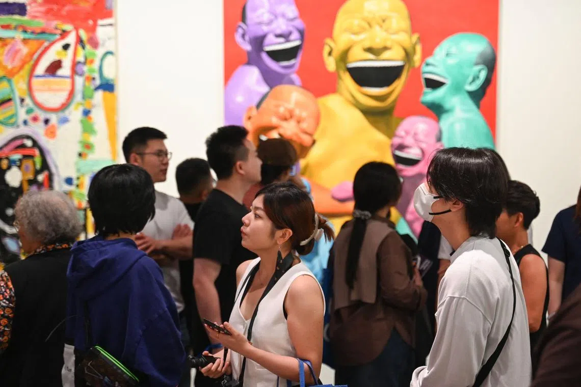 Visitors look at works by Chinese artist Yue Minjun on display at the Art Basel international art fair in Hong Kong on March 28, 2025. (Photo by Peter PARKS / AFP) / RESTRICTED TO EDITORIAL USE - MANDATORY MENTION OF THE ARTIST UPON PUBLICATION - TO ILLUSTRATE THE EVENT AS SPECIFIED IN THE CAPTION