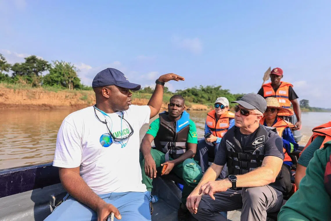 Aristide Takoukam Kamla (L), a marine biologist, researcher and conservationist specialising in the African manatee, talks to tourists and other biologists on a boat in Dizangue, on December 10, 2024. Ever since his first hard-won sightings of African manatees, award-winning marine biologist Aristide Takoukam Kamla has been devoted to protecting the little known and at risk mammals. African manatees are found in fresh water along the coast of western Africa, such as in Cameroon's vast Lake Ossa where the researcher first saw them more than 10 years ago. (Photo by Daniel Beloumou Olomo / AFP)