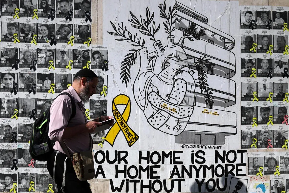 A man walking next to memorial pictures of hostages, most of whom were kidnapped during the deadly Oct 7 attack on Israel by Hamas, in Tel Aviv, Israel, on Sept 4.