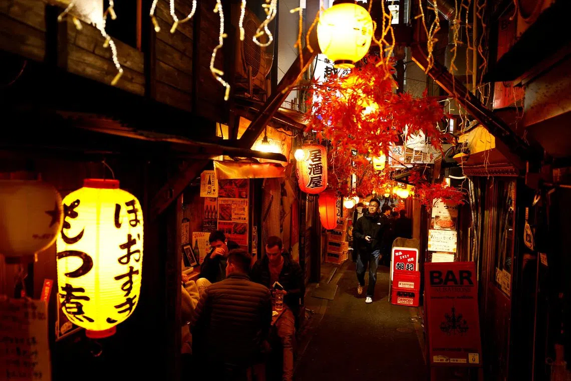Visitors walk at a Japanese Izakaya pub alley called Omoide Yokocho in Shinjuku, Tokyo.