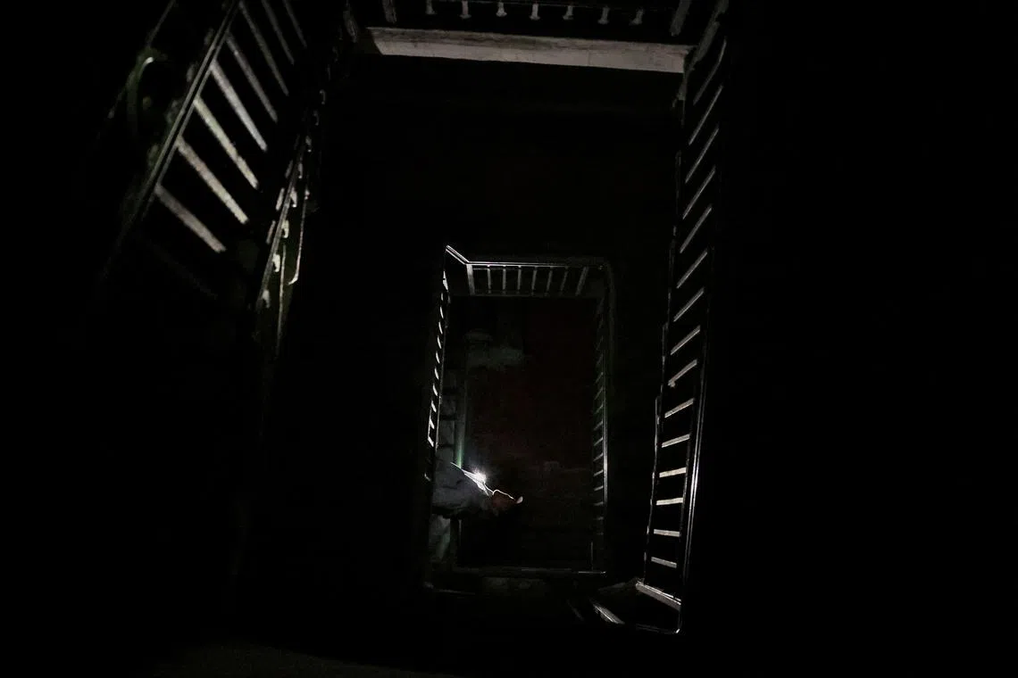 Ukrainian artist Yevhen Klymenko uses a flashlight to go downstairs during a blackout in Kyiv on June 5.