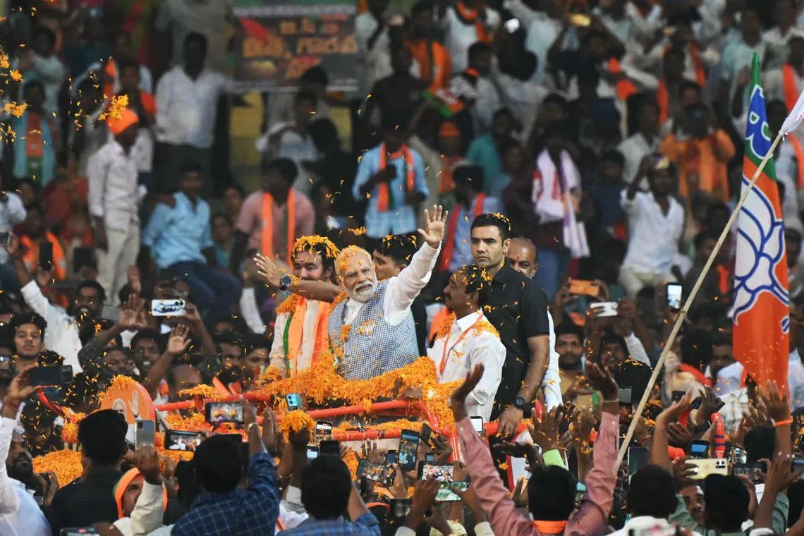 Indian Prime Minister Narendra Modi (C) waves to supporters as he arrives to attend a Bharatiya Janata Party (BJP) campaign meeting ahead of the Telangana state elections at Lal Bahadur Stadium in Hyderabad on November 7, 2023. (Photo by NOAH SEELAM / AFP)