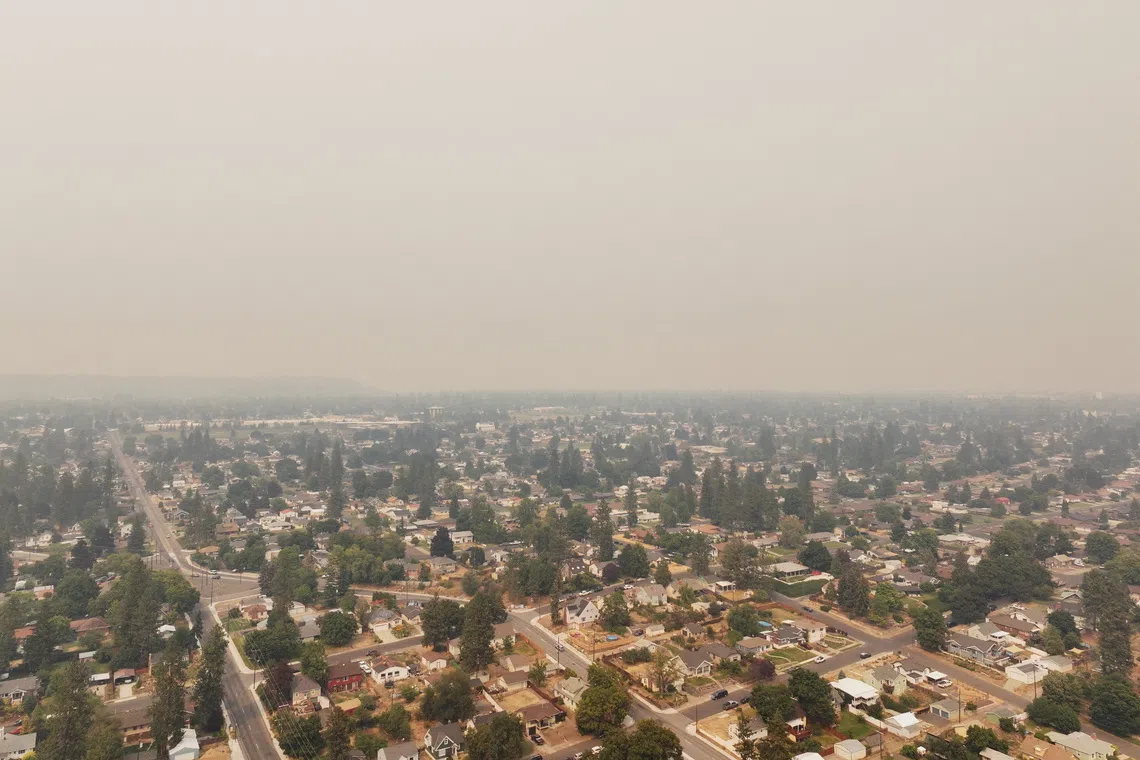 A hazy aerial view of a suburban neighborhood with houses and trees under a smoggy sky.