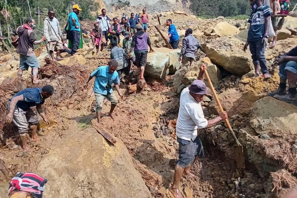 epa11373826 A handout photo made available by the International Organzation for Migration (IOM), shows local inhabitants digging in the rubble using spades and wooden sicks to serach for missing relatives at the landslide site in Tuliparo village, Yambali Ward, Maip Muli LLG, Porgera District,Papua New Guinea, 26 May 2024. (Issued 27 may 2024). According to a senior official with the IOM, on 26 May, more than 670 people are feared dead, after a landslide hit the Higlands region of Papua New Guinea on early 24 May. " the community in Yambali village, situated at the foot of a mountain in the remote Enga Province, is buried under between six to eight metres of soil. 150 houses are believed to be buried" he added.  EPA-EFE/MOHAMUD OMER/IOM/ HANDOUT  HANDOUT EDITORIAL USE ONLY/NO SALES HANDOUT EDITORIAL USE ONLY/NO SALES