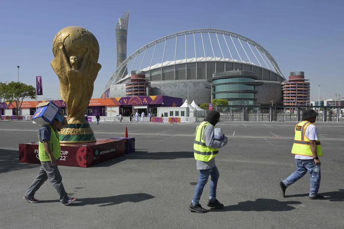 Workers walk past the Khalifa International Stadium in Doha ahead of the Qatar 2022 World Cup football tournament, which begins on Sunday.