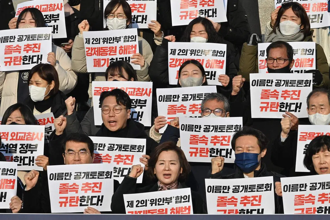 South Korean opposition lawmakers and supporters of the victims of Japan's wartime forced labour hold placards reading "We oppose the Yoon Seok-yeol government's humiliating solution to the forced labour issue!" during a protest against a public hearing on the issue at the National Assembly in Seoul on January 12, 2023. - South Korea said on January 12 it was moving to resolve a lingering diplomatic dispute with Japan over wartime forced labour, as Seoul seeks closer ties with Tokyo to counter North Korean aggression. (Photo by Jung Yeon-je / AFP)