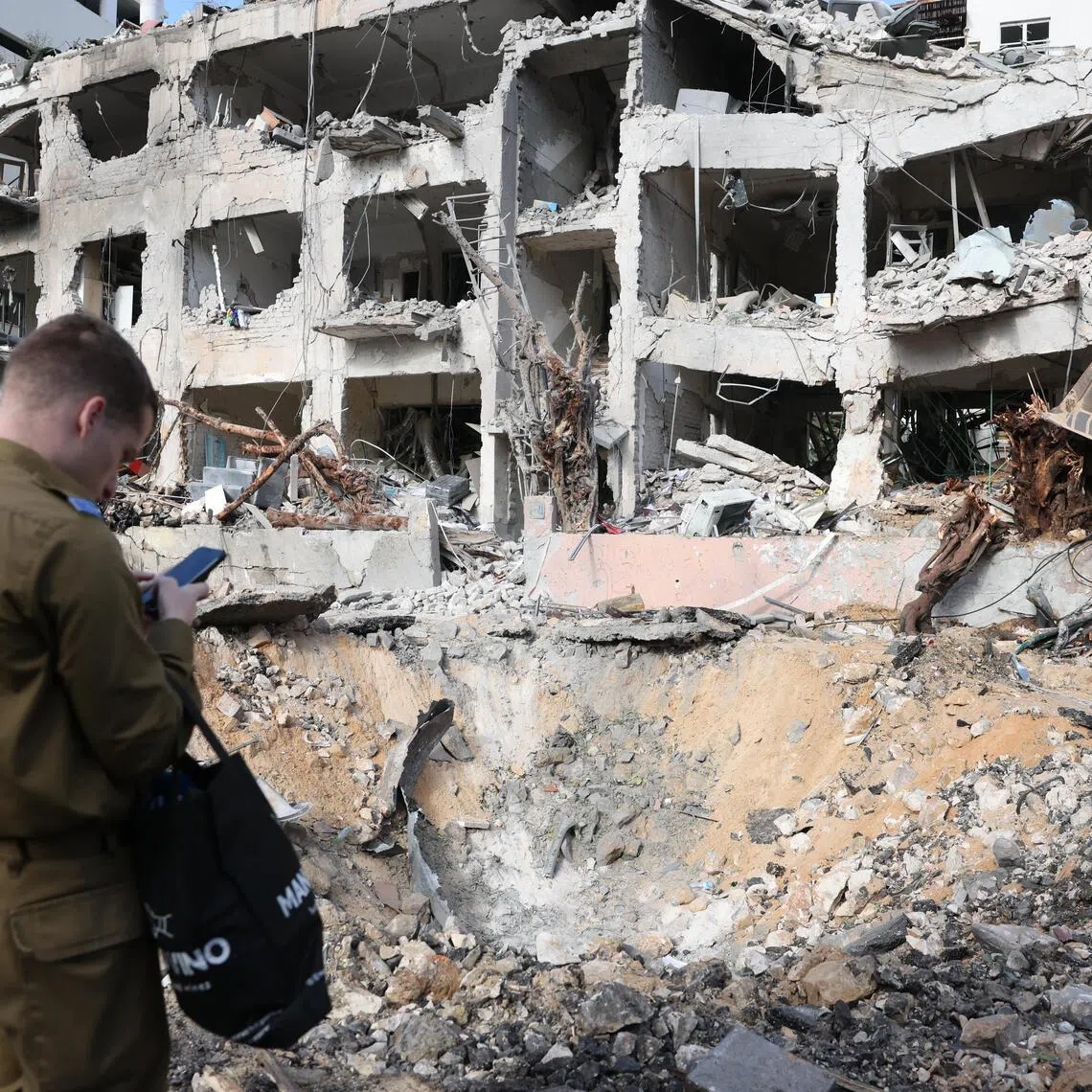 Emergency services personnel inspect the damage at the scene of a building that was struck by an Iranian missile in Tel Aviv, Israel.