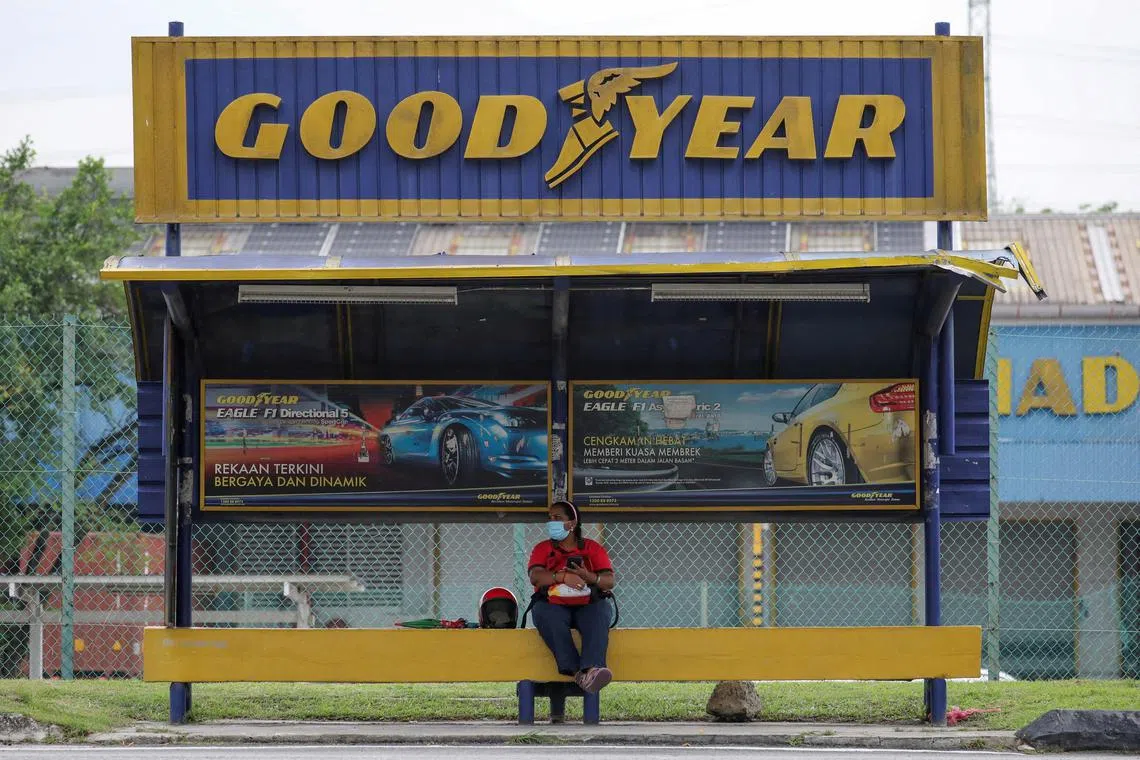 A woman sits at a bus stop outside Goodyear’s factory in Shah Alam, Malaysia in this May 6, 2021 file photo. 