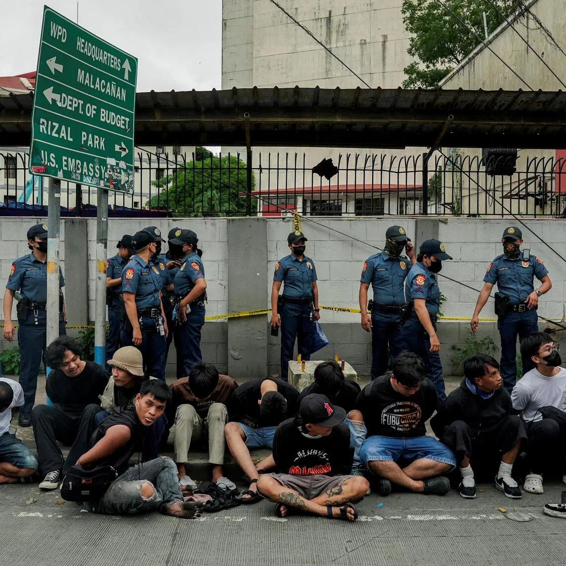 Protesters sitting on the ground after getting caught by police officers during a protest denouncing what they call corruption linked to flood control projects, in Manila on Sept 21. 