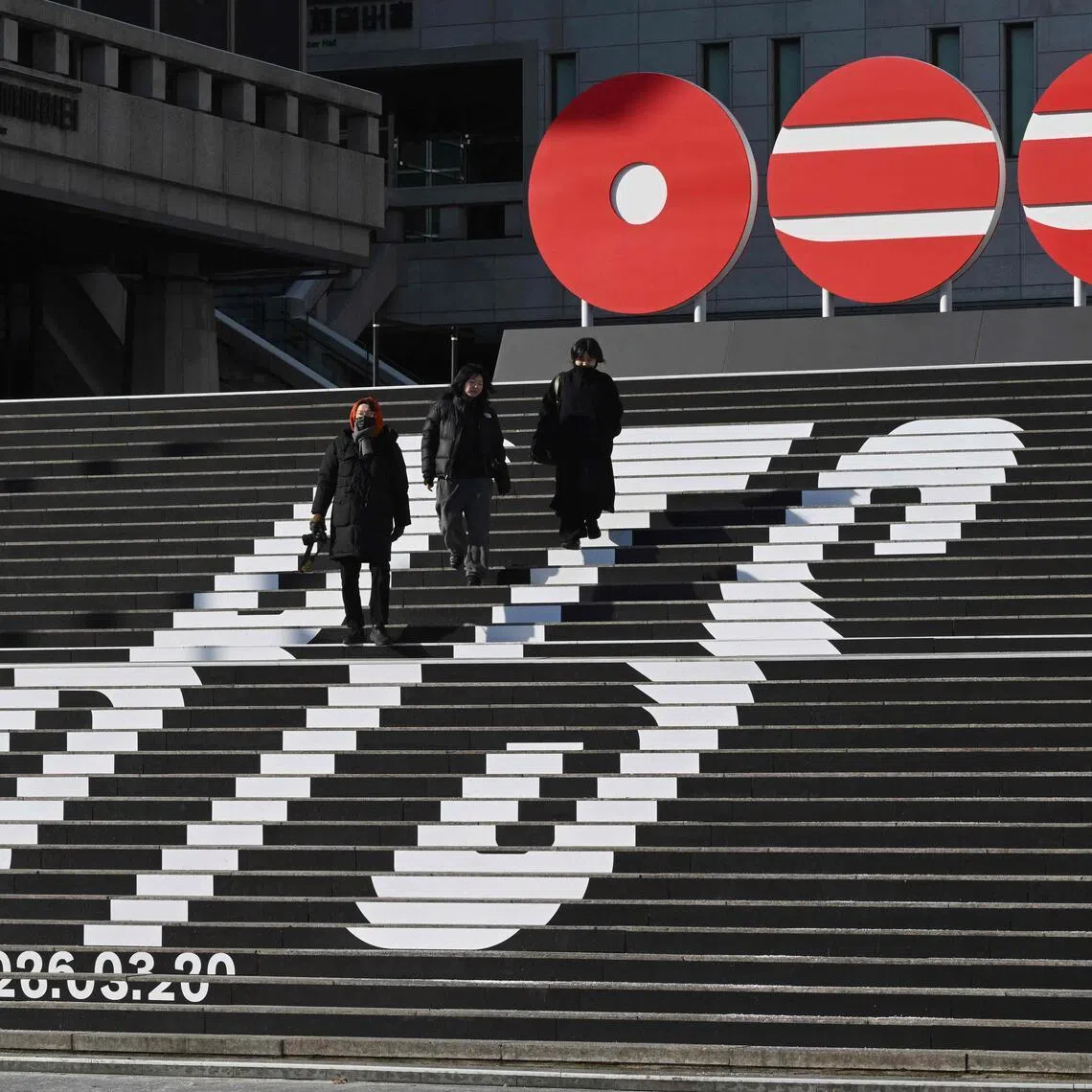 Pedestrians walk along the stairs displayed with the logo of BTS' 2026 album and release date at Gwanghwamun Square in Seoul on Jan 14, 2026. 