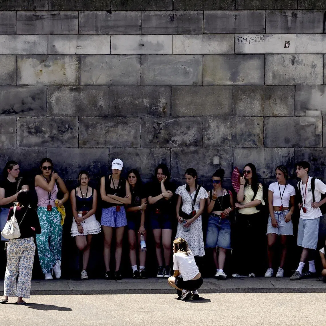 Tourists rest in the shade along the banks of the Spree River on a summer day in Berlin.
