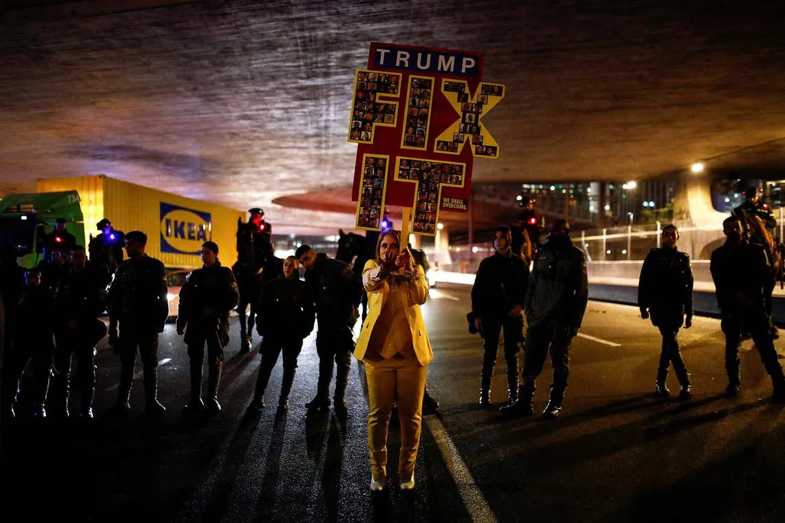 A woman holding a sign referring to US President Donald Trump, as people block an access road to Tel Aviv during a protest in support of the hostages kidnapped during the deadly Oct 7, 2023 attack by Hamas, in Tel Aviv, Israel, Feb 10, 2025. 