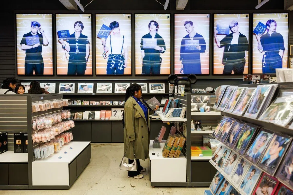 Customers browse K-pop band BTS merchandise at a souvenir store in Seoul, South Korea, on Wednesday, March 18, 2026. After a near four-year hiatus, K-pop megastars BTS are back with a new album, a live-stream deal with Netflix Inc. — and a world tour that could rival Taylor Swift’s record-breaking $2 billion Eras Tour in earnings. Photographer: SeongJoon Cho/Bloomberg