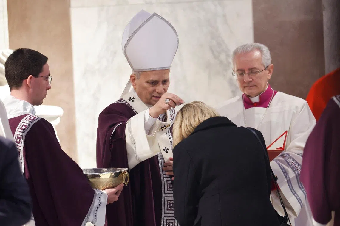 Pope Leo XIV puts ash on a faithful's head during the Ash Wednesday Mass at the Santa Sabina Basilica in Rome, Italy, February 18, 2026. REUTERS/Remo Casilli