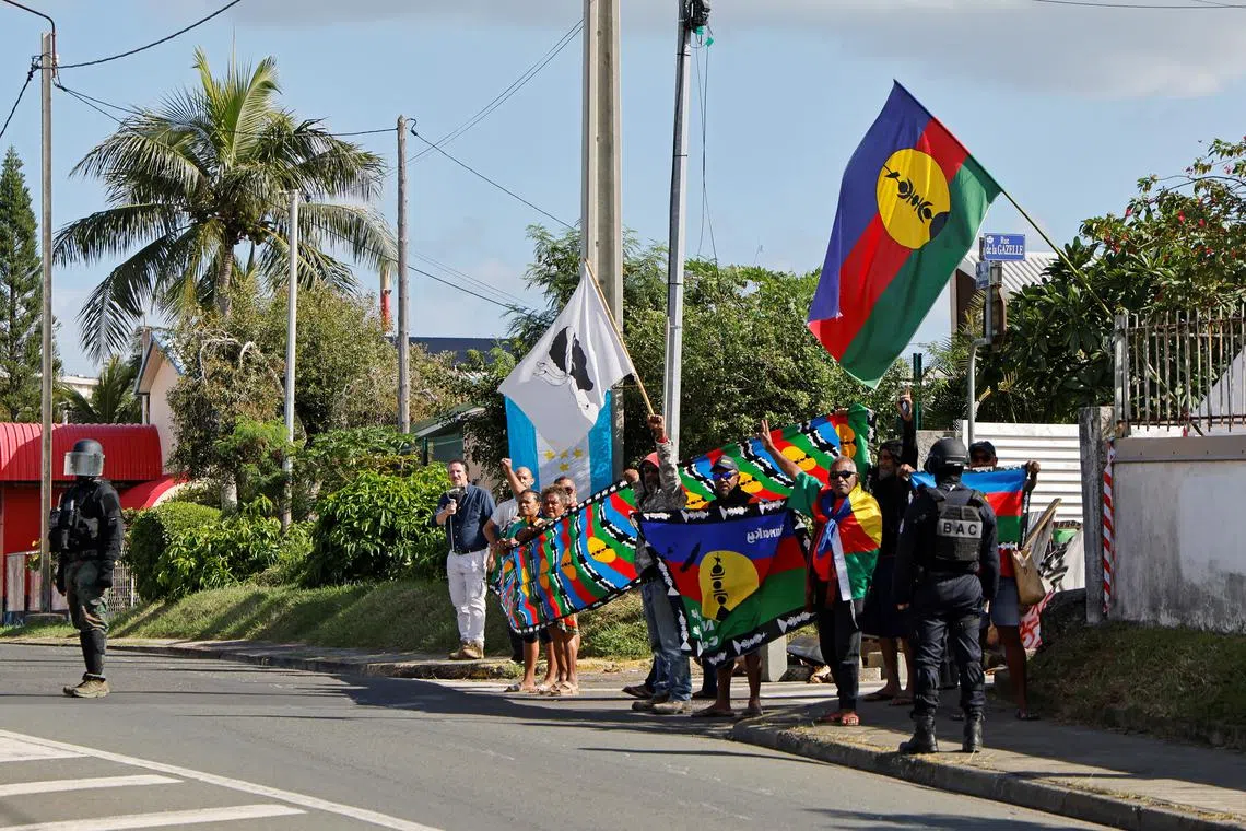 FILE PHOTO: People demonstrate as French President Emmanuel Macron's motorcade drives past in Noumea, France's Pacific territory of New Caledonia on May 23, 2024.     LUDOVIC MARIN/Pool via REUTERS/File Photo