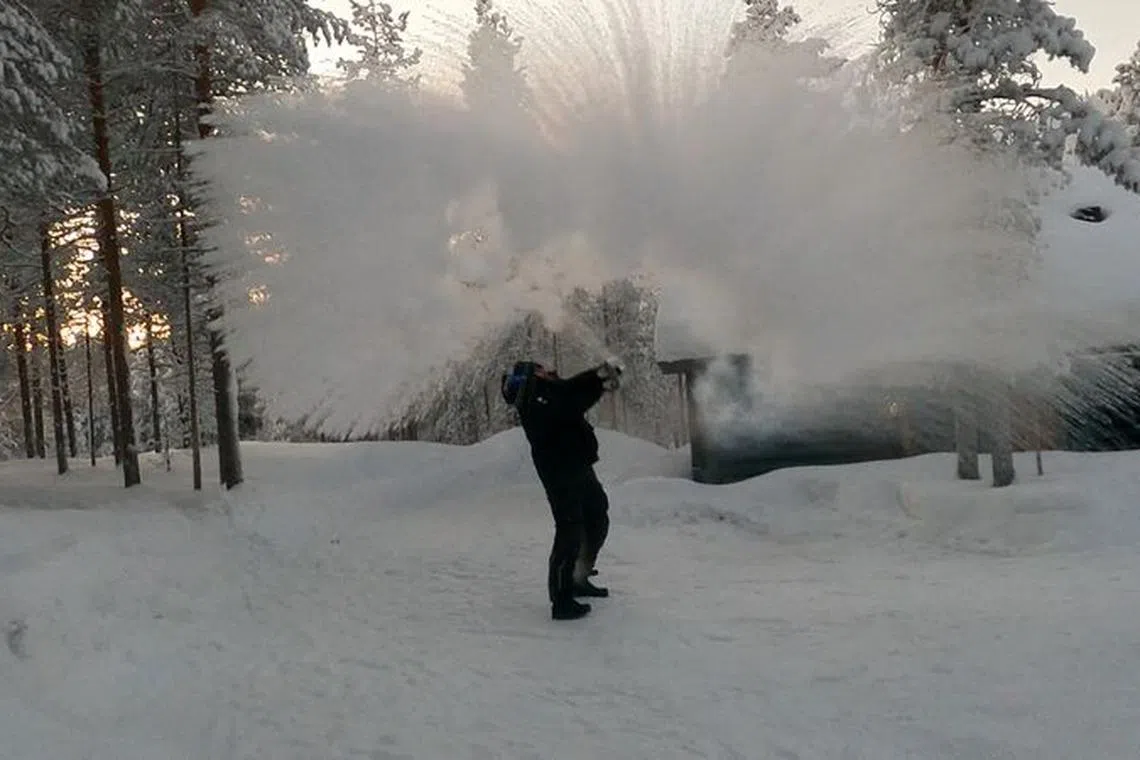 A person throws boiling water into the air, which turns into steam, following cold weather, in Pyhatunturi, Finland January 1, 2024, in this screen grab obtained from social media video. Lauri Untamo/via REUTERS/File Photo
